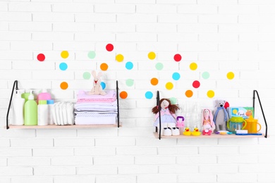 Baby accessories on shelves near white brick wall