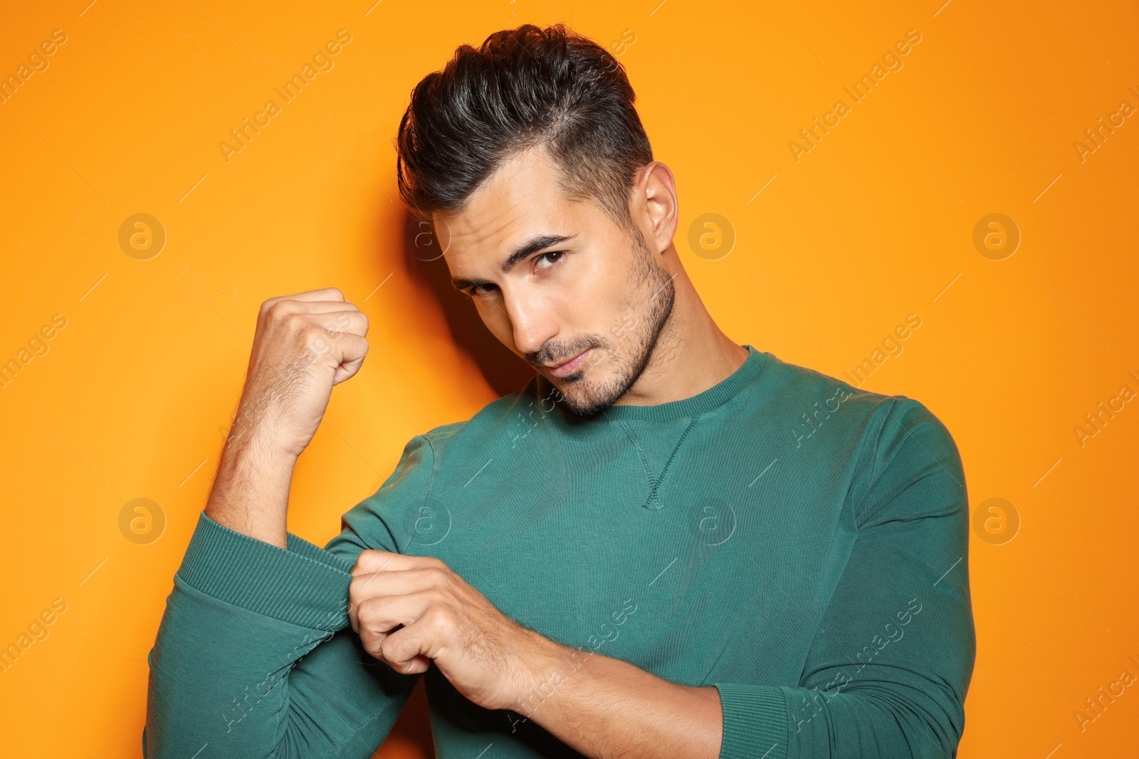 Photo of Young man with trendy hairstyle posing on color background