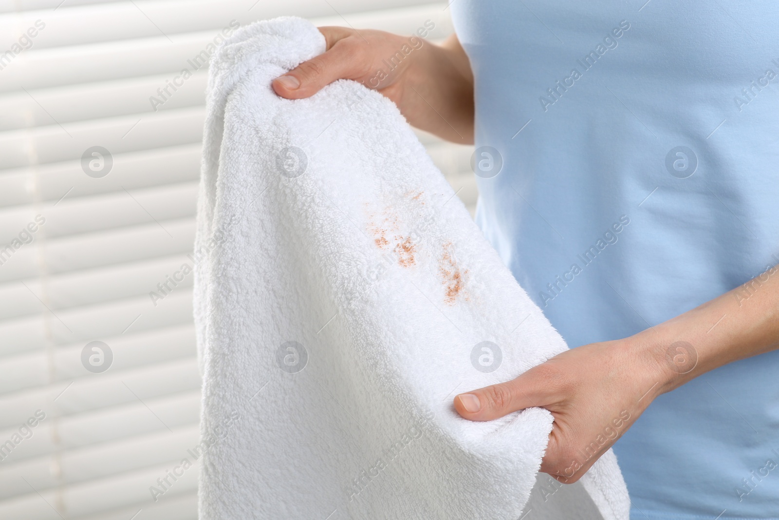 Photo of Woman holding terry towel with makeup spot indoors, closeup