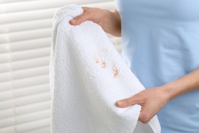 Photo of Woman holding terry towel with makeup spot indoors, closeup