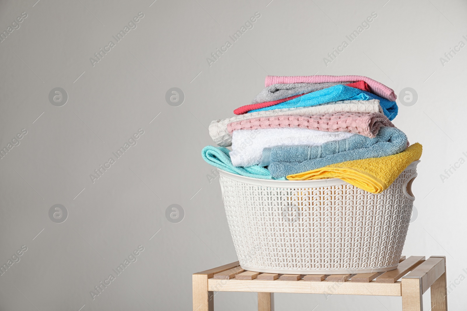 Photo of Laundry basket with clean towels on table against light background. Space for text