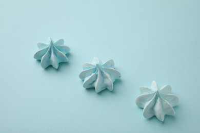 Photo of Delicious meringue cookies on light blue background, above view