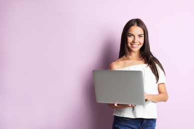 Photo of Young woman with modern laptop on color background