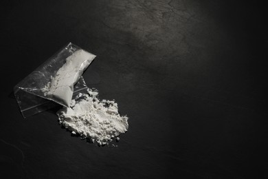 Photo of Plastic bag with hard drug on dark textured background, top view. Space for text