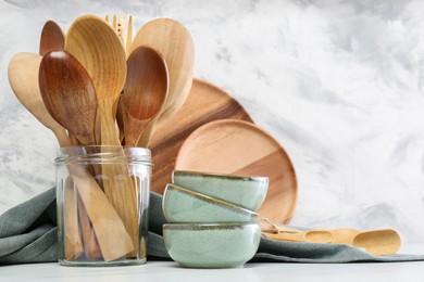 Photo of Different dishware and utensils on white marble table against textured wall