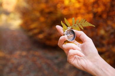 Traveler searching direction with compass in wilderness, closeup. Space for text