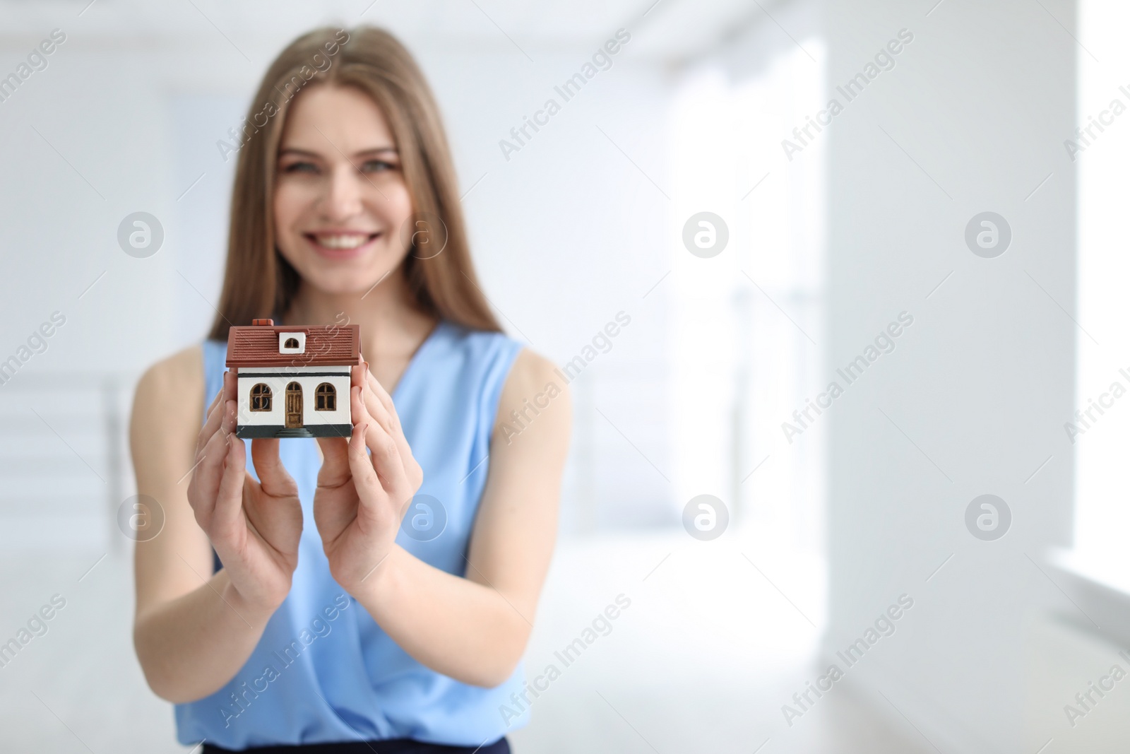 Photo of Beautiful real estate agent with house model indoors