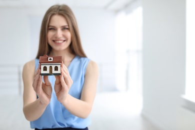 Beautiful real estate agent with house model indoors