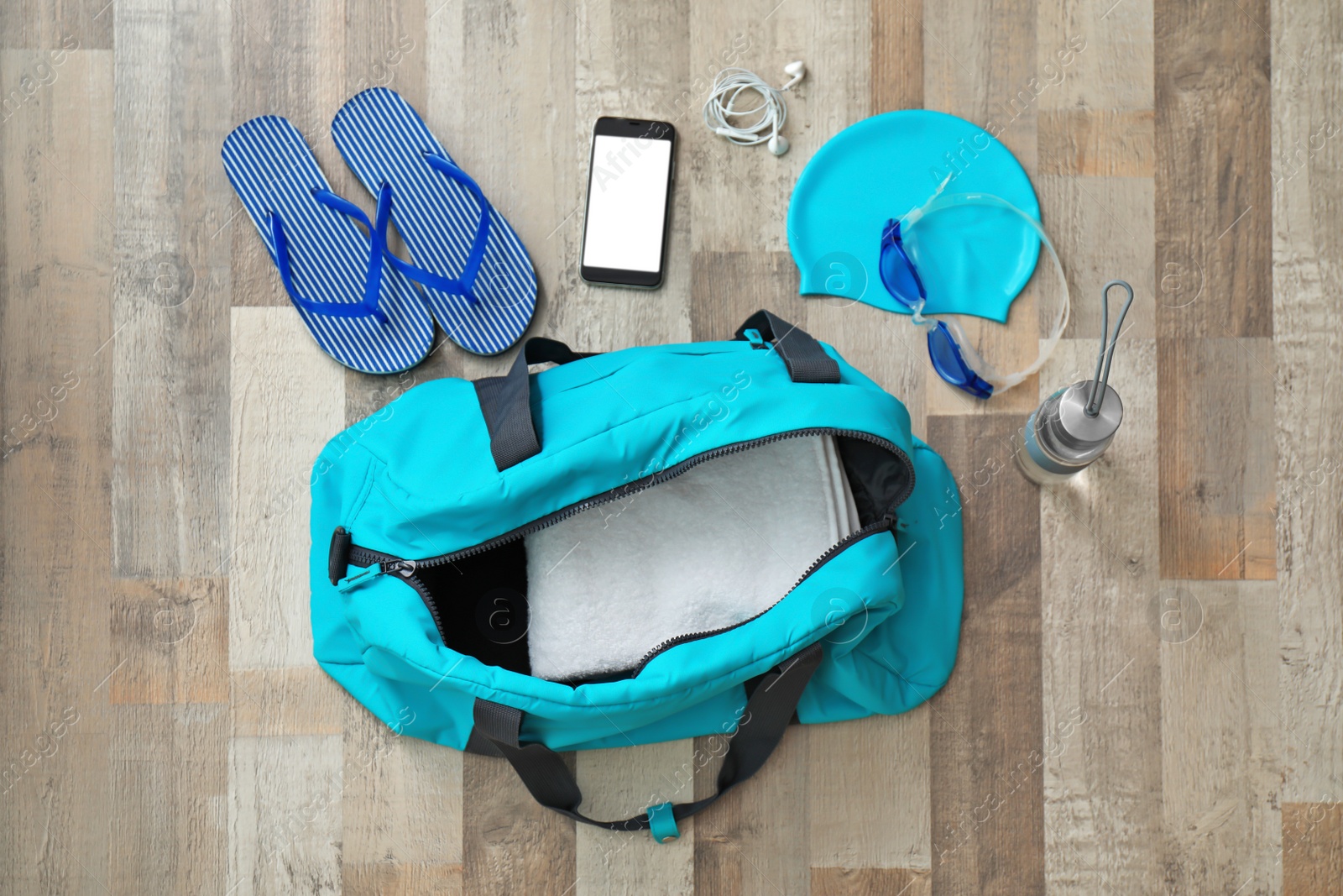 Photo of Flat lay composition with sports bag and equipment for swimming pool on wooden floor, top view