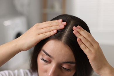 Photo of Woman examining her hair and scalp indoors, closeup