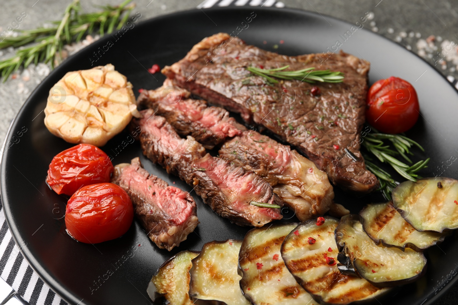 Photo of Delicious grilled beef steak with vegetables and spices on table, closeup