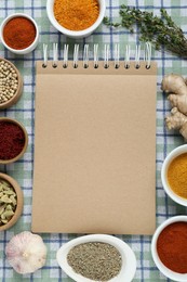 Blank recipe book and different ingredients on checkered tablecloth, flat lay. Space for text