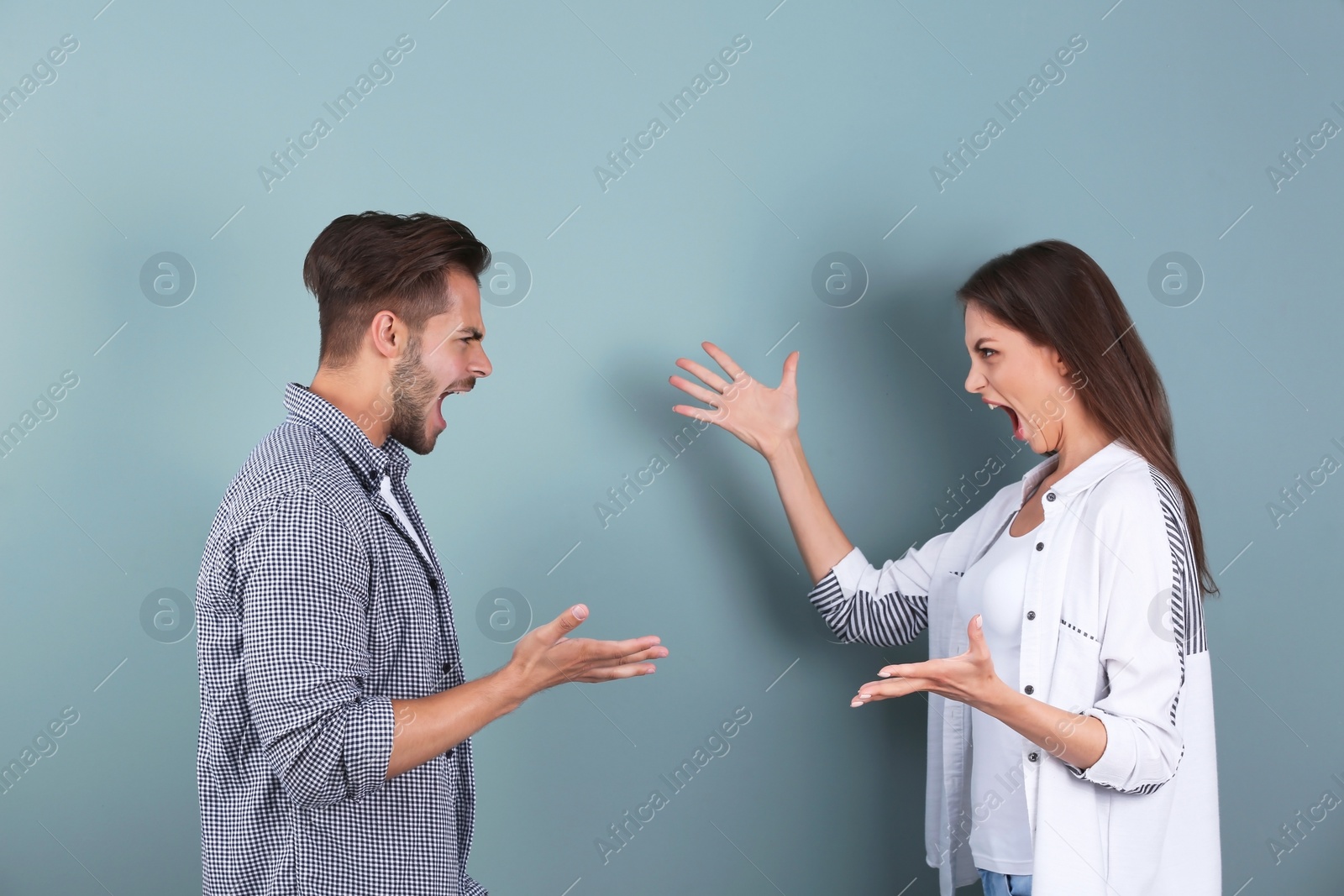 Photo of Young couple having argument on color background. Relationship problems