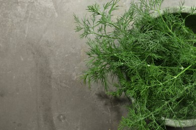 Photo of Fresh green dill in bowl on grey table, top view. Space for text