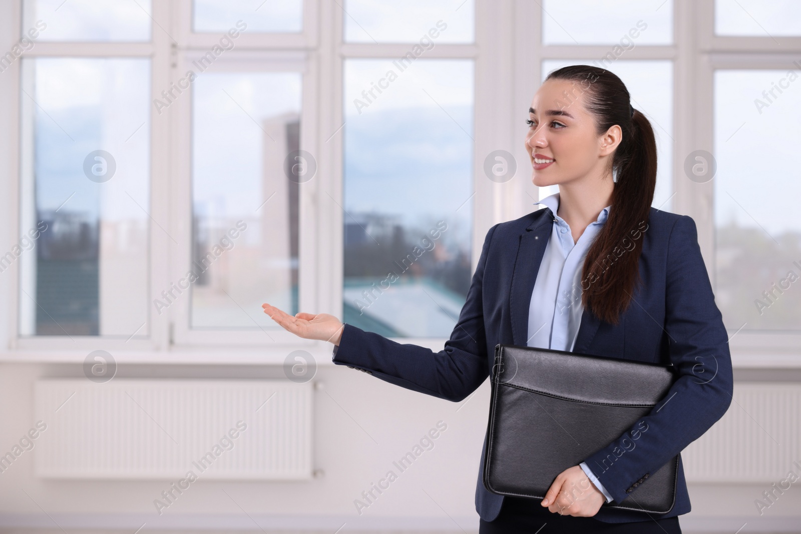 Photo of Happy real estate agent with leather portfolio showing new apartment. Space for text