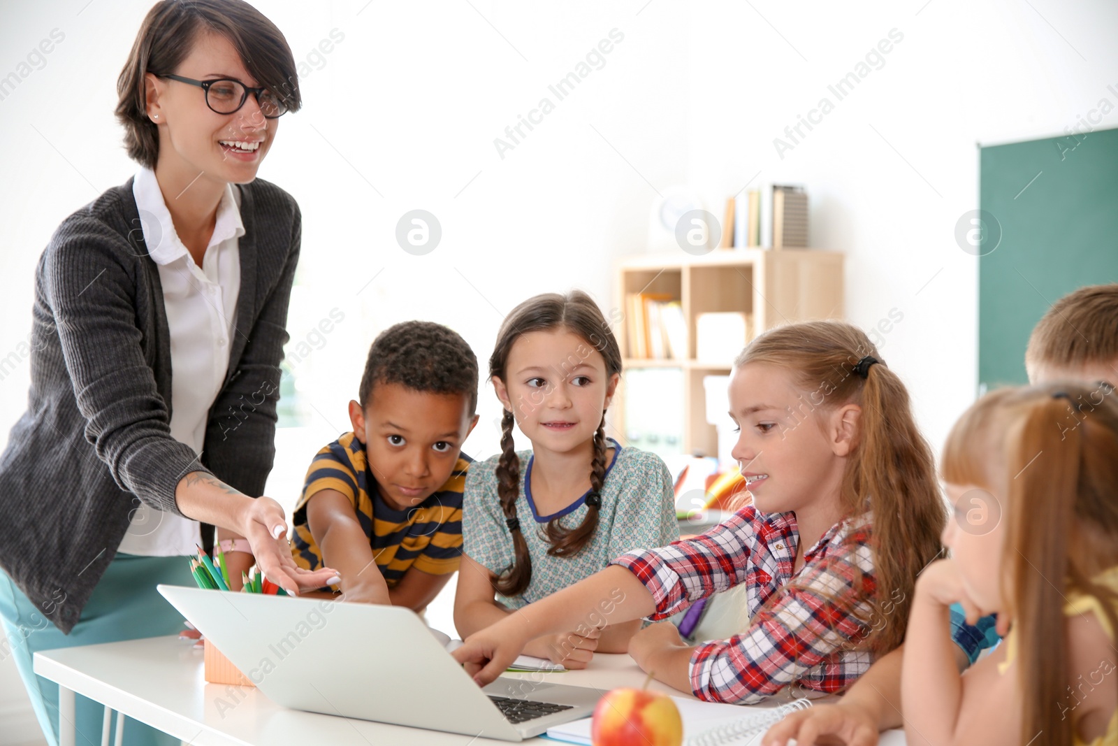 Photo of Female teacher helping children with assignment at school