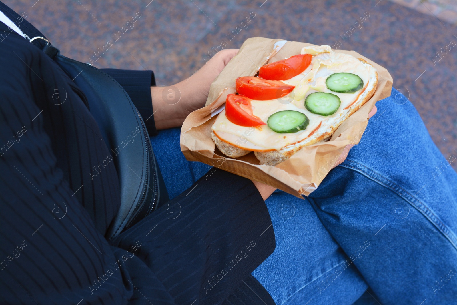 Photo of Woman holding tasty sandwich with vegetables outdoors, closeup. Street food