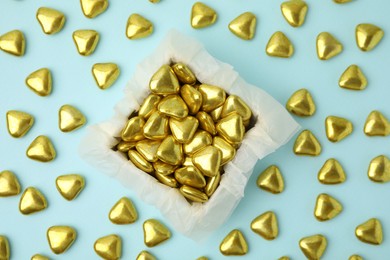 Photo of Box and delicious heart shaped candies on light blue background, flat lay