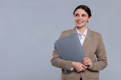 Photo of Smiling accountant with folders on grey background, space for text