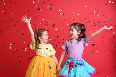 Photo of Adorable little children and falling confetti on red background