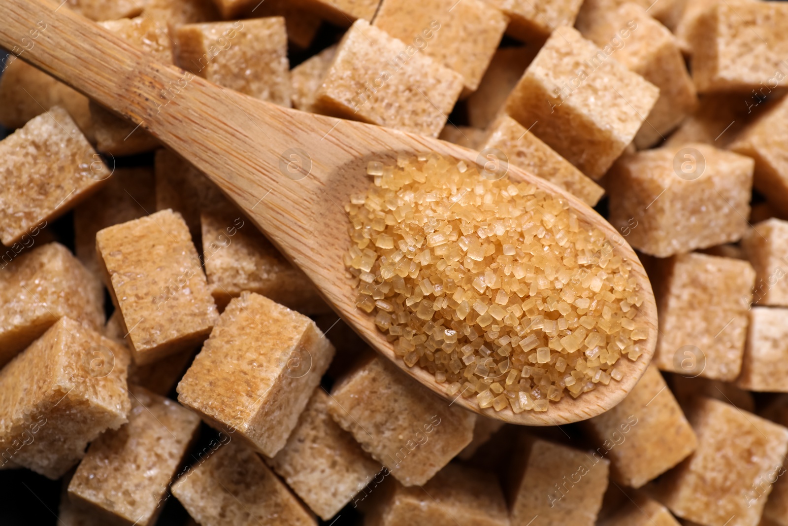 Photo of Wooden spoon on brown sugar cubes, top view