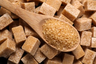 Wooden spoon on brown sugar cubes, top view