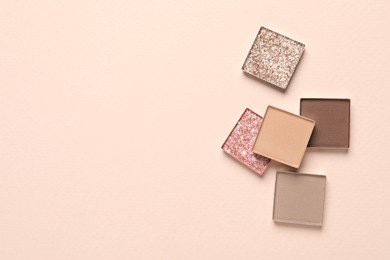 Different beautiful eye shadows on beige background, flat lay. Space for text