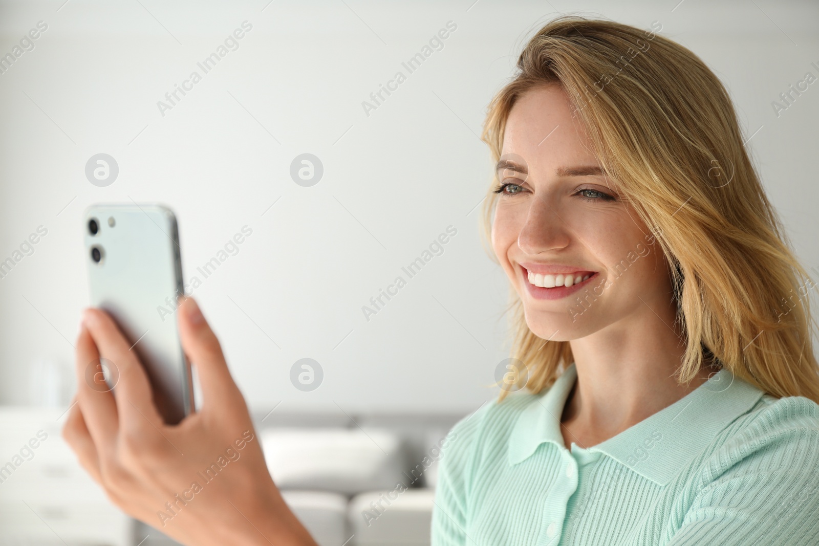 Photo of Young woman unlocking smartphone with facial scanner indoors. Biometric verification