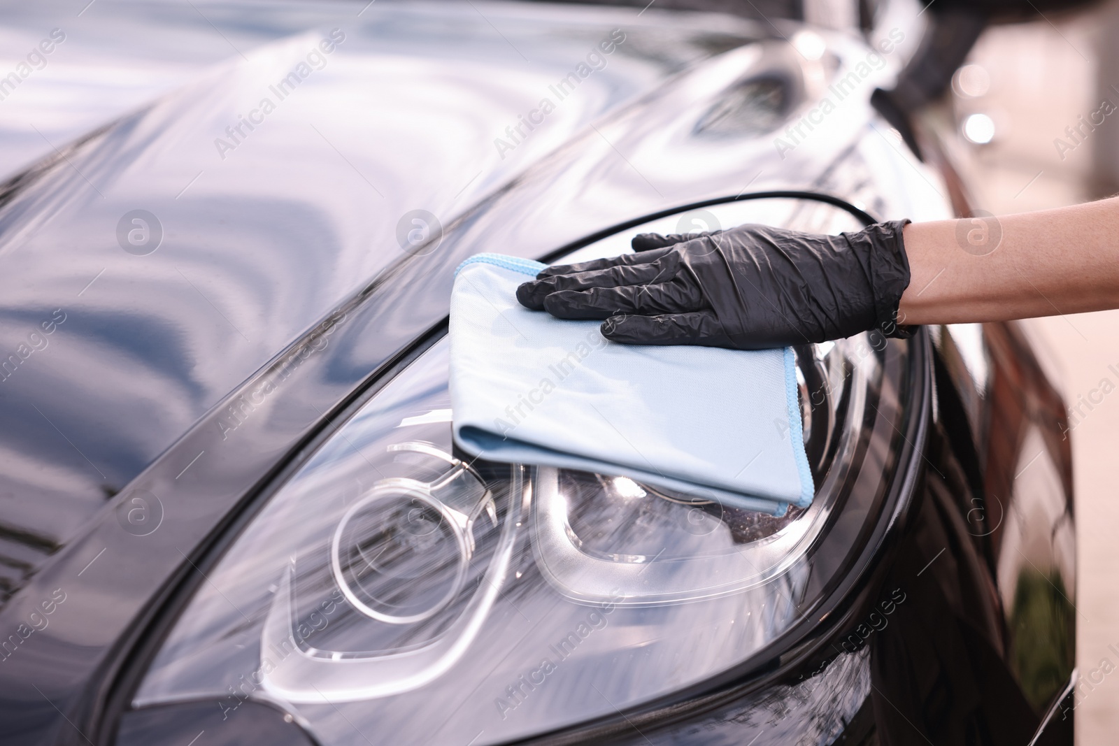 Photo of Woman wiping her modern car with rag, closeup