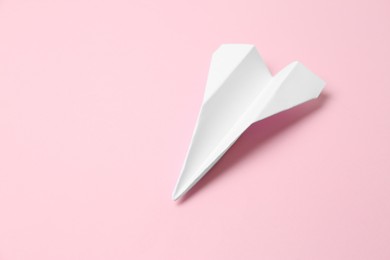Photo of Handmade paper plane on pink background, space for text