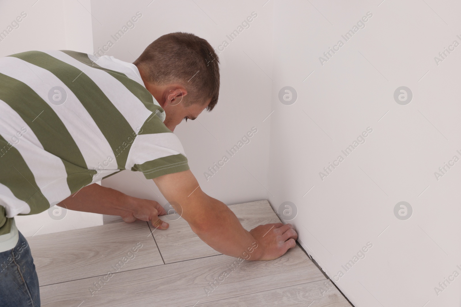 Photo of Professional worker installing new laminate flooring indoors