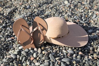 Photo of Beautiful hat with flip flops on pebbles outdoors