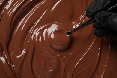 Person making tasty milk chocolate paste, top view