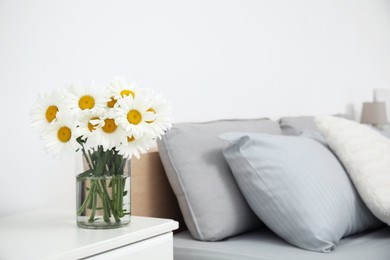 Photo of Bouquet of beautiful daisy flowers on table in bedroom, space for text