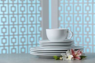 Set of clean dishware with flowers on light grey table, space for text