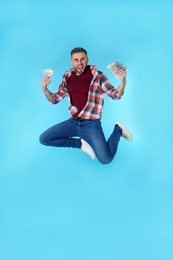 Happy young man with money jumping on color background. Space for text