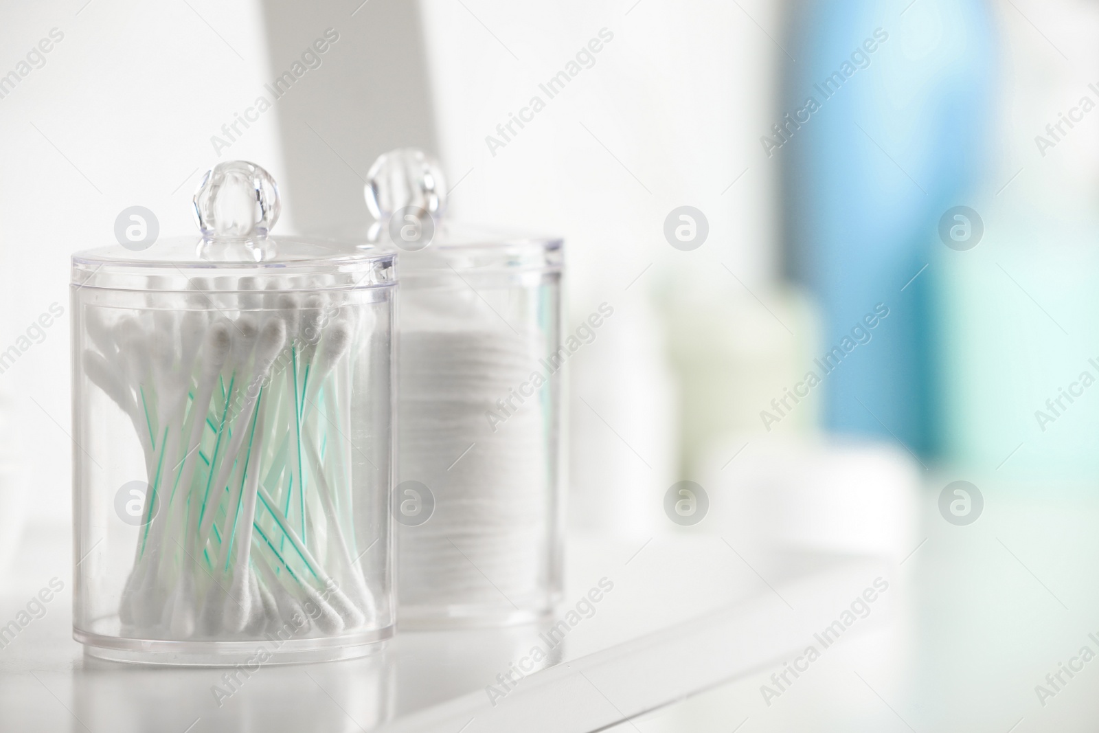 Photo of Containers with cotton swabs and pads on white shelf in bathroom, closeup. Space for text