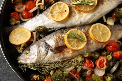 Photo of Baked fish with vegetables, rosemary and lemon on black textured table, top view