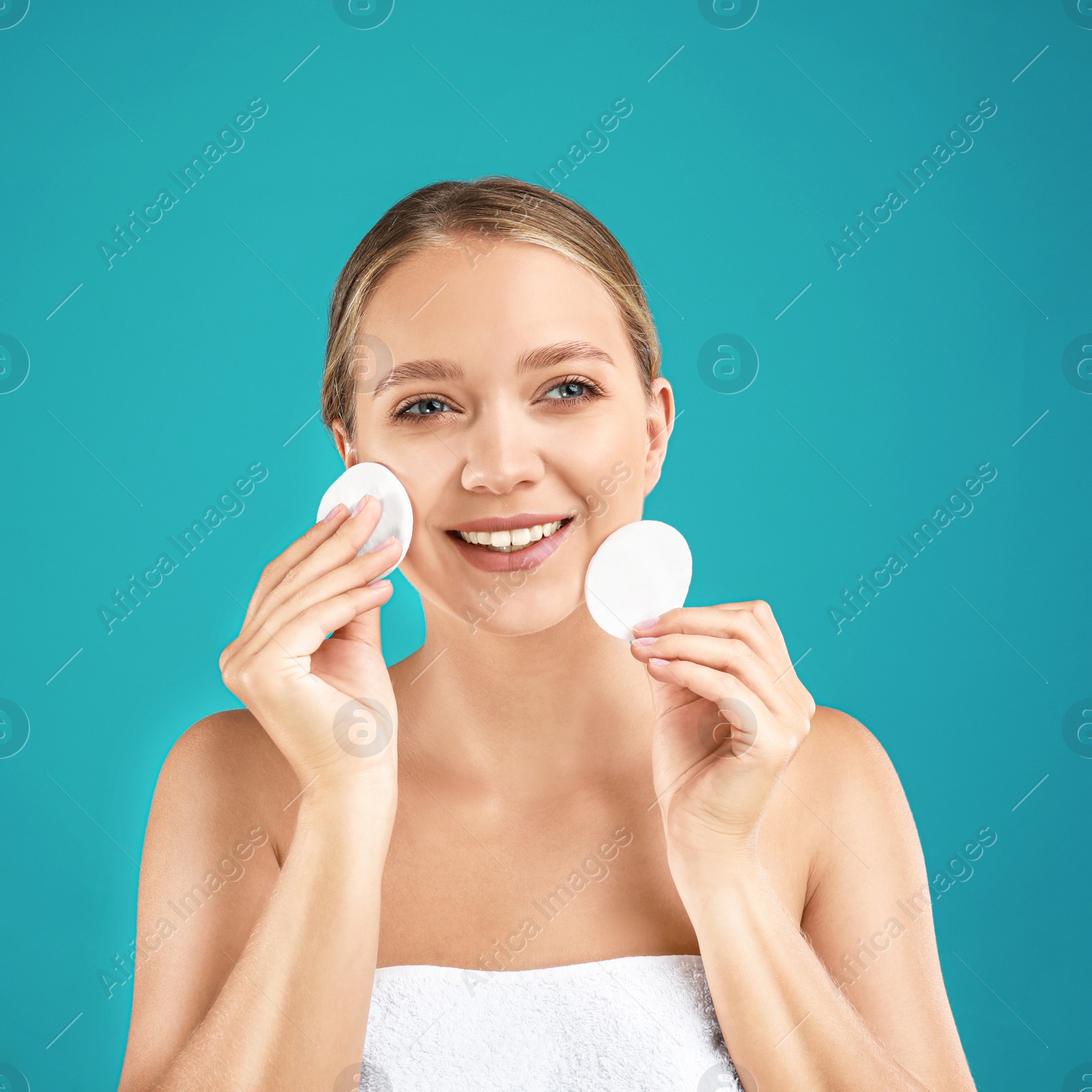 Photo of Beautiful young woman with cotton pads on turquoise background