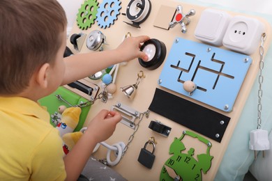 Little boy playing with busy board on bed