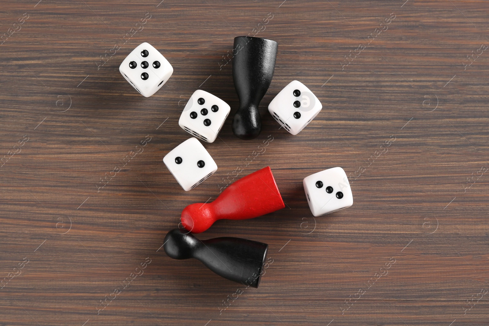 Photo of Many white dices and color game pieces on wooden table, flat lay