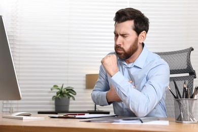 Photo of Sick man coughing at workplace in office. Cold symptoms