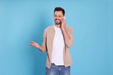 Photo of Man talking on phone against light blue background