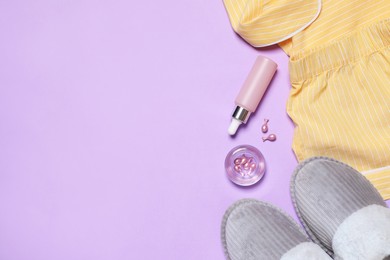 Flat lay composition with pajamas and skin care products on violet background, space for text