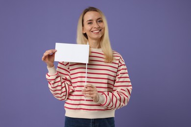 Photo of Happy woman with blank white flag on violet background. Mockup for design