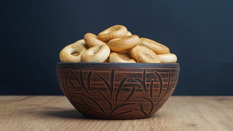 Photo of Bowl of tasty dry bagels (sushki) on wooden table