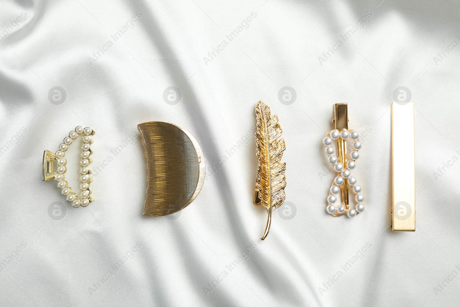 Photo of Beautiful different hair clips on white fabric, flat lay