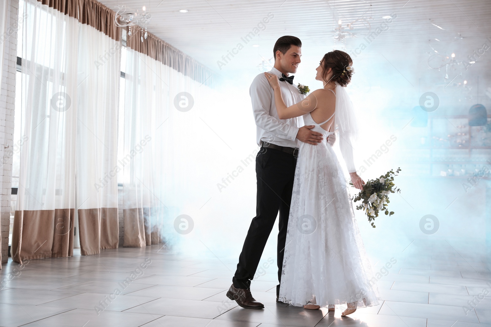 Photo of Happy newlywed couple dancing together in festive hall