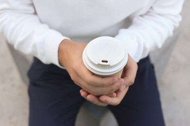 Photo of Coffee to go. Man with paper cup of drink outdoors, closeup