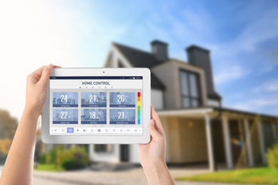 Image of Energy efficiency home control system. Woman using tablet to set temperature in different rooms, closeup